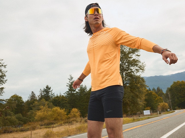 Medium shot of a man wearing Brooks Running orange long sleeve shirt